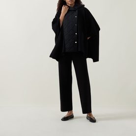 Model wearing Joseph Ribkoff black quilted jacket with wide-lapel collar, styled with black wide-leg trousers and flat loafers.