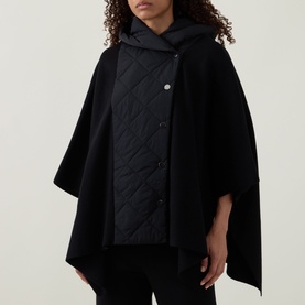Model wearing Joseph Ribkoff black cape jacket with quilted front panel, snap button fastening, and oversized hooded silhouette.