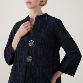 Model wearing Joseph Ribkoff navy textured jacket with crinkle finish, styled with a silver brooch, three-quarter sleeves.