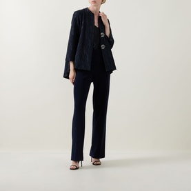 Model wearing Joseph Ribkoff navy jacket with subtle shimmer, styled with matching navy wide-leg trousers and black heeled sandals.