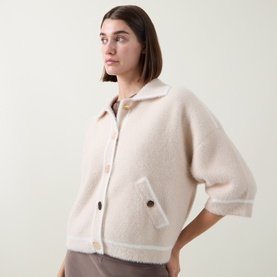 Model wearing Joseph Ribkoff Jacket in Oatmeal/Winter White, textured boucle fabric, short sleeves, button front, patch pockets, styled with grey