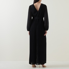 Model wearing Joseph Ribkoff black pleated wide-leg jumpsuit, back view showing V-back neckline and sheer long sleeves.