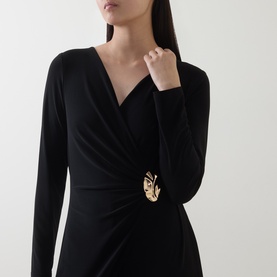 Model wearing Joseph Ribkoff black jumpsuit with wrap-style V-neckline, long sleeves, and gold brooch detail at waist.
