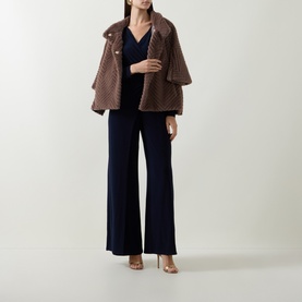 Model wearing Joseph Ribkoff Jumpsuit in Midnight Blue wide-leg style, styled with a brown textured coat and strappy heels.