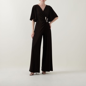 Model wearing Joseph Ribkoff bronze jumpsuit with flutter sleeves, wrap-style V-neckline, belted waist, and wide-leg trousers, styled with black
