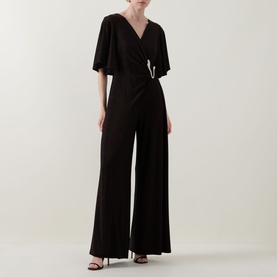 Model wearing Joseph Ribkoff bronze jumpsuit with flutter sleeves, wrap-style V-neckline, and wide-leg trousers, styled with black heeled sandals.