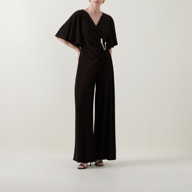 Model wearing Joseph Ribkoff bronze jumpsuit with flutter sleeves, wrap front, embellished waist detail and wide-leg trousers, styled with black