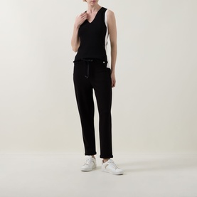 Model wearing Joseph Ribkoff black and birch sleeveless V-neck top with black drawstring trousers and white trainers.