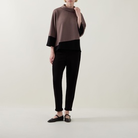 Model wearing Joseph Ribkoff Mink/Black top with contrast hem, paired with black tapered trousers and black flat shoes.