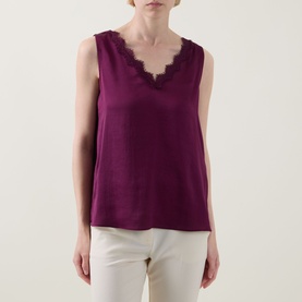 Model wearing Joseph Ribkoff Berry Burst sleeveless top with scalloped lace V-neckline, styled with white trousers.