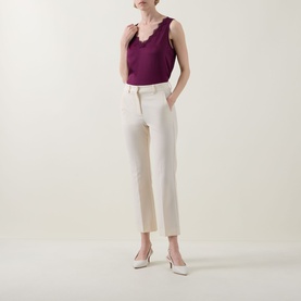 Model wearing Joseph Ribkoff Berry Burst sleeveless top with lace neckline, styled with cream tailored trousers and nude heels.