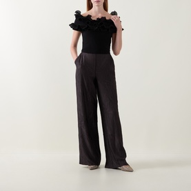 Model wearing Joseph Ribkoff black off-shoulder ruffled top with wide-leg dark trousers and metallic flats.
