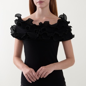 Model wearing Joseph Ribkoff black off-shoulder top with layered organza ruffle neckline and short sleeves.