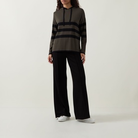 Model wearing Joseph Ribkoff Striped Hoodie in avocado and black with asymmetric hem and side slits, styled with wide-leg black trousers.