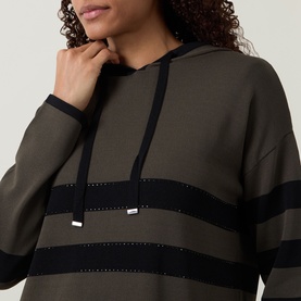 Model wearing Joseph Ribkoff Striped Hoodie in avocado and black with rhinestone stripe detail, drawstring hood, and long sleeves.