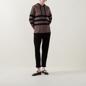 Model wearing Joseph Ribkoff mink and black striped hoodie top with black cropped trousers and black flat shoes.
