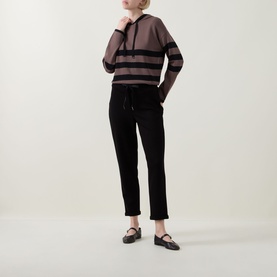 Model wearing Joseph Ribkoff mink and black striped hoodie top with black drawstring trousers and black flat shoes.
