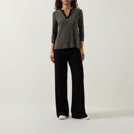 Model wearing Joseph Ribkoff Contrast Neckline Top in Avocado/Black with open collar, long sleeves, styled with wide-leg black trousers.