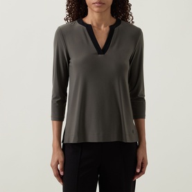 Model wearing Joseph Ribkoff Contrast Neckline Top in Avocado with black V-neckline trim, three-quarter sleeves, paired with black trousers.