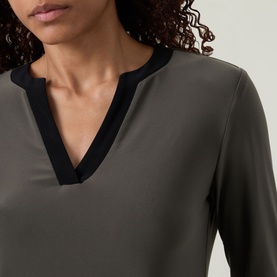 Model wearing Joseph Ribkoff Contrast Neckline Top in Avocado with black contrast V-neckline trim, long sleeves, 96% polyester fabric.