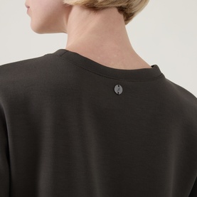 Model wearing Joseph Ribkoff top in Avocado, back view showing round neckline with small metal logo charm detail.