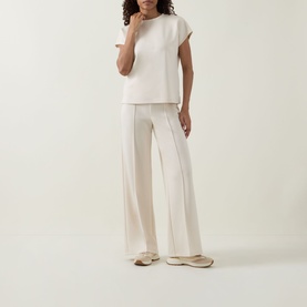 Model wearing Joseph Ribkoff Relaxed Scuba Top in Birch, styled with matching wide-leg trousers and flat mule shoes.
