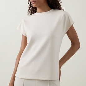 Model wearing Joseph Ribkoff Relaxed Scuba Top in birch, featuring short cap sleeves, crew neck, and straight hemline, styled with wide-leg trousers.