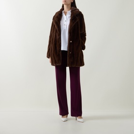 Model wearing Joseph Ribkoff Vanilla top styled with brown faux fur coat, burgundy wide-leg trousers and white heels.