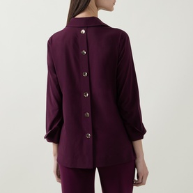 Model wearing Joseph Ribkoff elderberry top, rear view showing button-down back detail and three-quarter sleeves, styled with matching trousers.