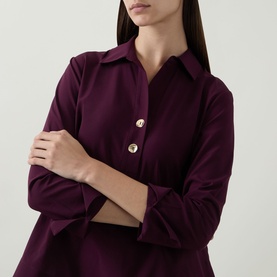 Model wearing Joseph Ribkoff Top in Elderberry, featuring a pointed collar and gold-tone buttons, long sleeves with folded cuffs.