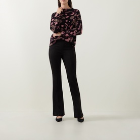 Model wearing Joseph Ribkoff Abstract Print Embellished Sweater in black/multi, boat neck, long sleeves, styled with black flare trousers and heels.