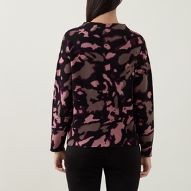 Model wearing Joseph Ribkoff Abstract Print Embellished Sweater in black and pink abstract camo print, long sleeves, straight hem, back view.