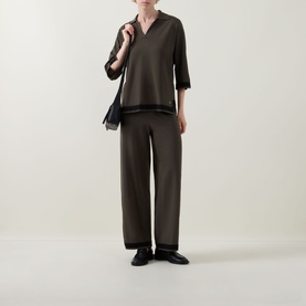 Model wearing Joseph Ribkoff Avocado/Black V-neck top with black trim, styled with matching wide-leg trousers and black loafers.