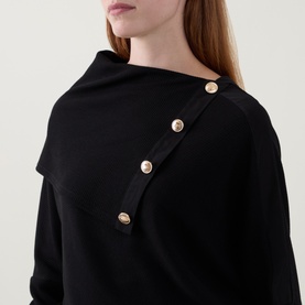 Model wearing Joseph Ribkoff black top with asymmetric neckline and diagonal gold button detail