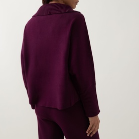 Model wearing Joseph Ribkoff Rib Knit Button Sweater in Elderberry, showing back view with extended collar, long sleeves and dipped hemline, styled