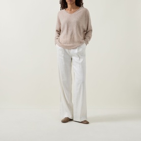 Model wearing Joseph Ribkoff oatmeal melange cashmere V-neck sweater, styled with white wide-leg trousers and taupe loafers.