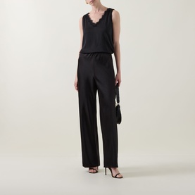 Model wearing Joseph Ribkoff black sleeveless top with lace trim V-neckline, styled with wide-leg satin trousers and black heeled sandals.