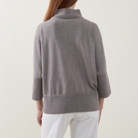 Model wearing Joseph Ribkoff Top in Taupe Melange, back view, mock neck, 3/4 sleeves, ribbed hem, styled with white trousers