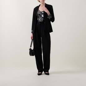 Model wearing Joseph Ribkoff grey/multi printed top styled with black blazer, wide-leg trousers, and block-heel mules, carrying small black bag.