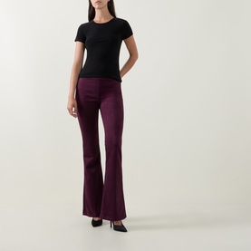 Model wearing Joseph Ribkoff Solid Fitted T-Shirt in black with crew neck, styled with burgundy flared trousers and black heels.