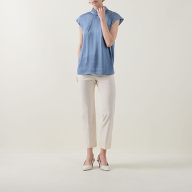 Model wearing Joseph Ribkoff Chambray Top with mock neck and cap sleeves, styled with white cropped trousers and nude slingback heels.