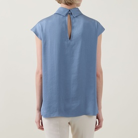 Model wearing Joseph Ribkoff Top in Chambray blue, rear view showing keyhole back detail and short cap sleeves, styled with cream trousers.