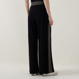 Model wearing Joseph Ribkoff wide-leg trousers in black with avocado side panels and contrast elasticated waistband, rear view.