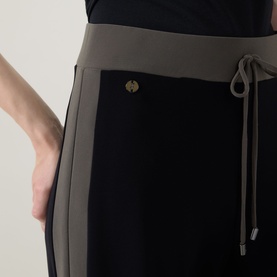 Model wearing Joseph Ribkoff trousers in black and avocado, with contrast waistband, drawstring tie and gold button detail.