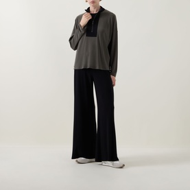 Model wearing Joseph Ribkoff black wide-leg trousers styled with an avocado and black contrast top and white trainers.