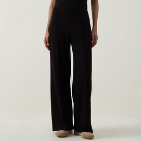 Model wearing Joseph Ribkoff Wide Leg Scuba Trousers in black with pleated front and elasticated waist, styled with beige shoes.