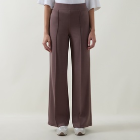 Model wearing Joseph Ribkoff mink wide-leg trousers with front seam detail, styled with white top and white trainers.