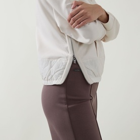 Model wearing Joseph Ribkoff Trousers in Mink, styled with a cream quilted zip jacket. Close-up of waist and hip detail.