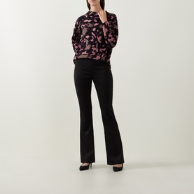 Model wearing Joseph Ribkoff Velour Flared-Leg Trousers in black with pressed creases, styled with a pink floral top and black heels.