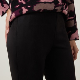 Model wearing Joseph Ribkoff Velour Flared-Leg Trousers in black, mid-rise pull-on style with pressed creases, styled with pink floral top
